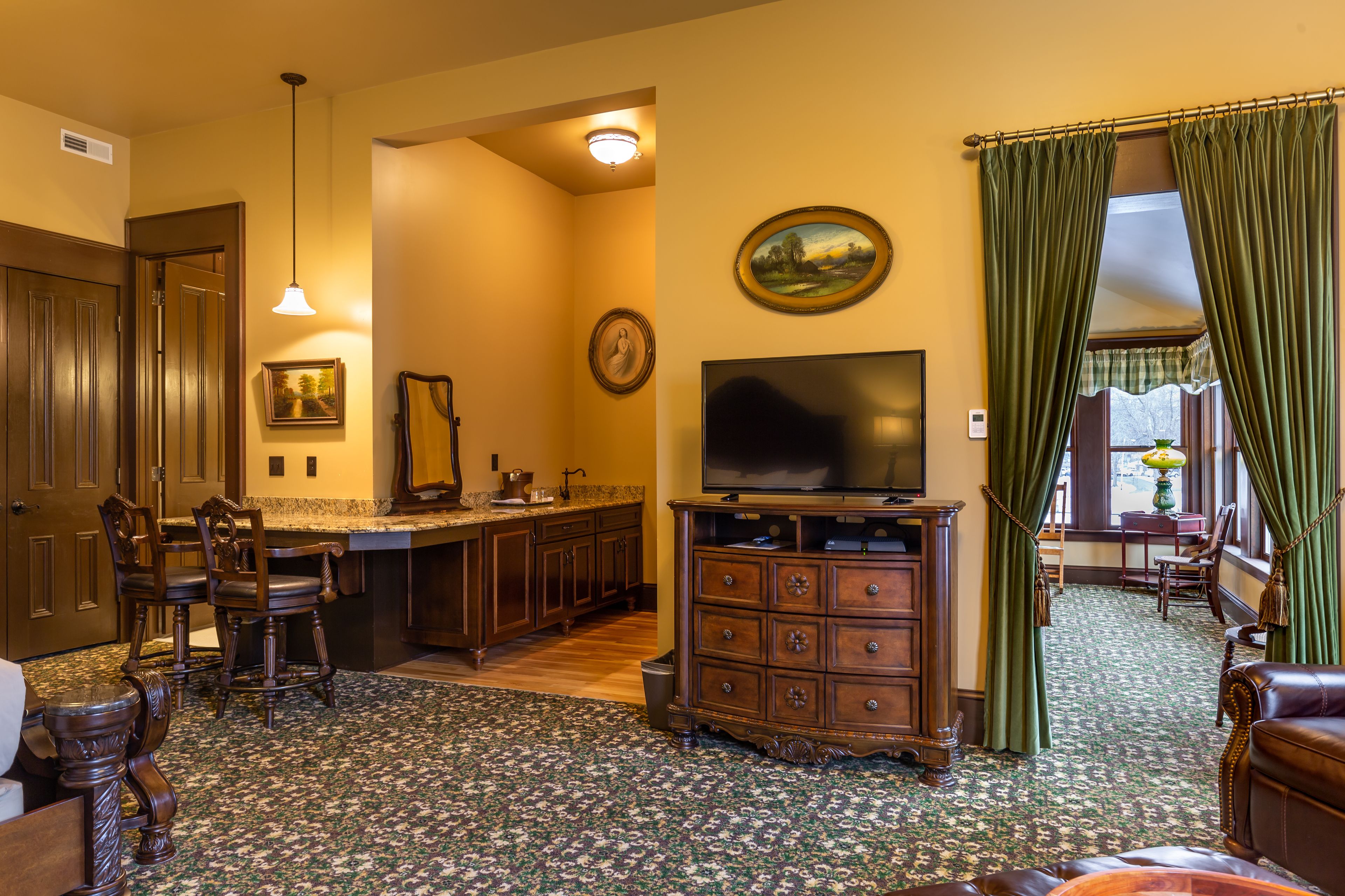 Sala de estar com televisão, móveis de madeira, tapete estampado e um espaço de jantar com cadeiras e mesa.