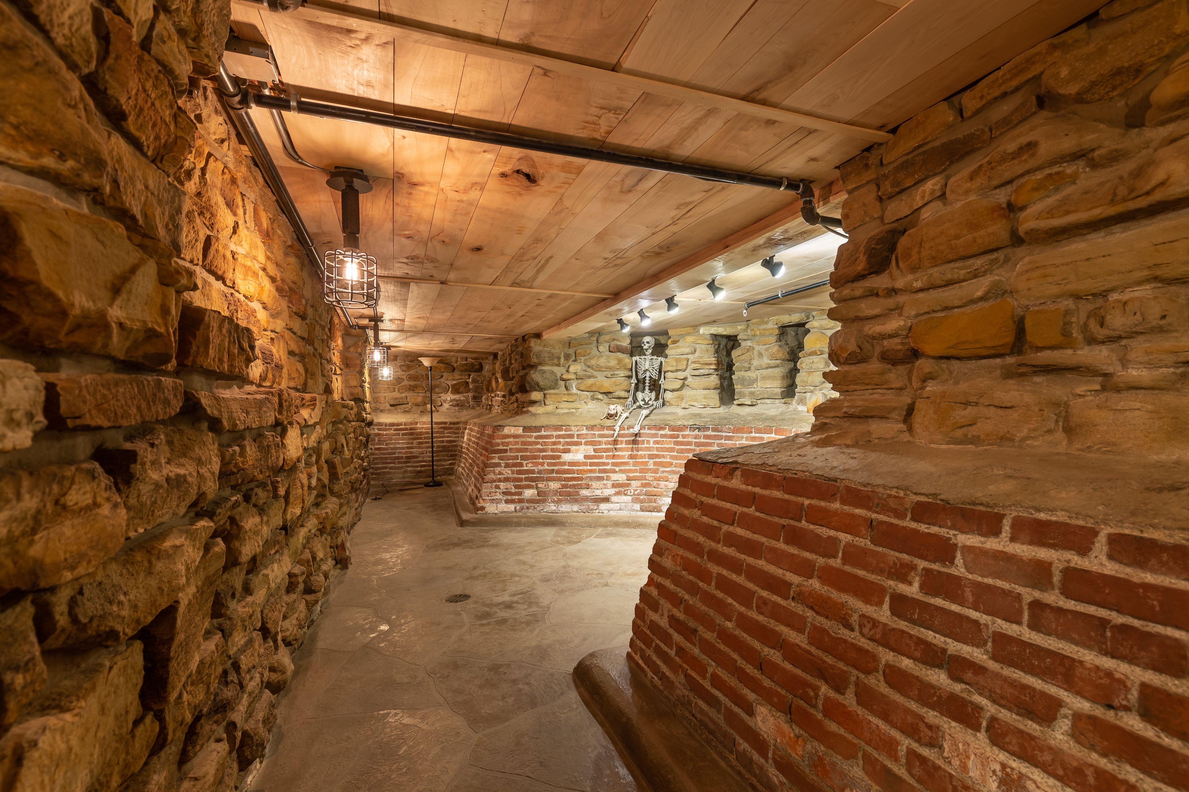 A stone-walled corridor with wooden beams and brick walls.