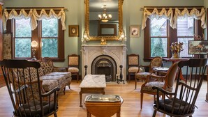 Una habitación tradicional con chimenea, espejo decorativo y muebles clásicos.