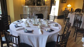 A formal dining room with a round table set for a meal, surrounded by wooden chairs.
