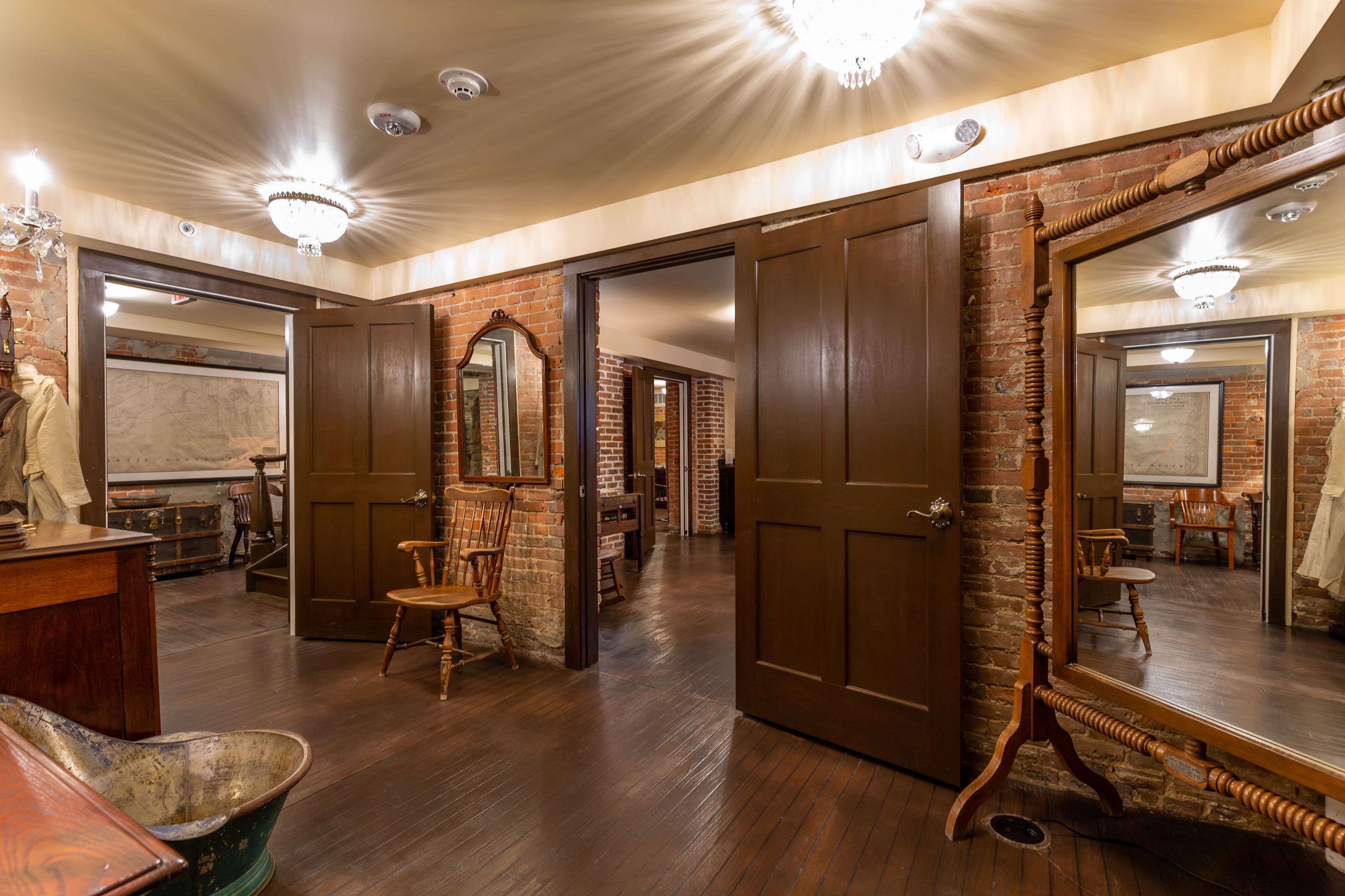 A room with wooden floors, a large mirror, and a wooden door.