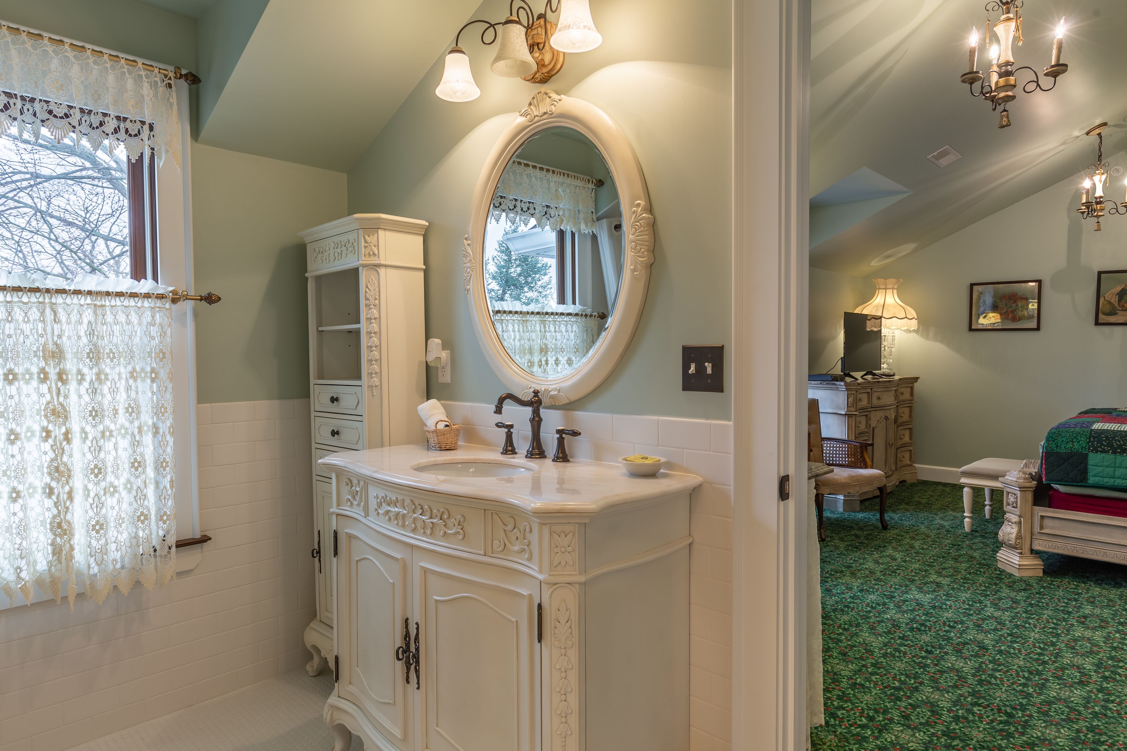 A bathroom with a white vanity, an ornate mirror, and a green carpeted floor.