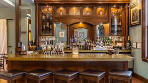 Una zona de bar con encimera de granito pulido, varias botellas de licor y una amplia variedad de vasos.