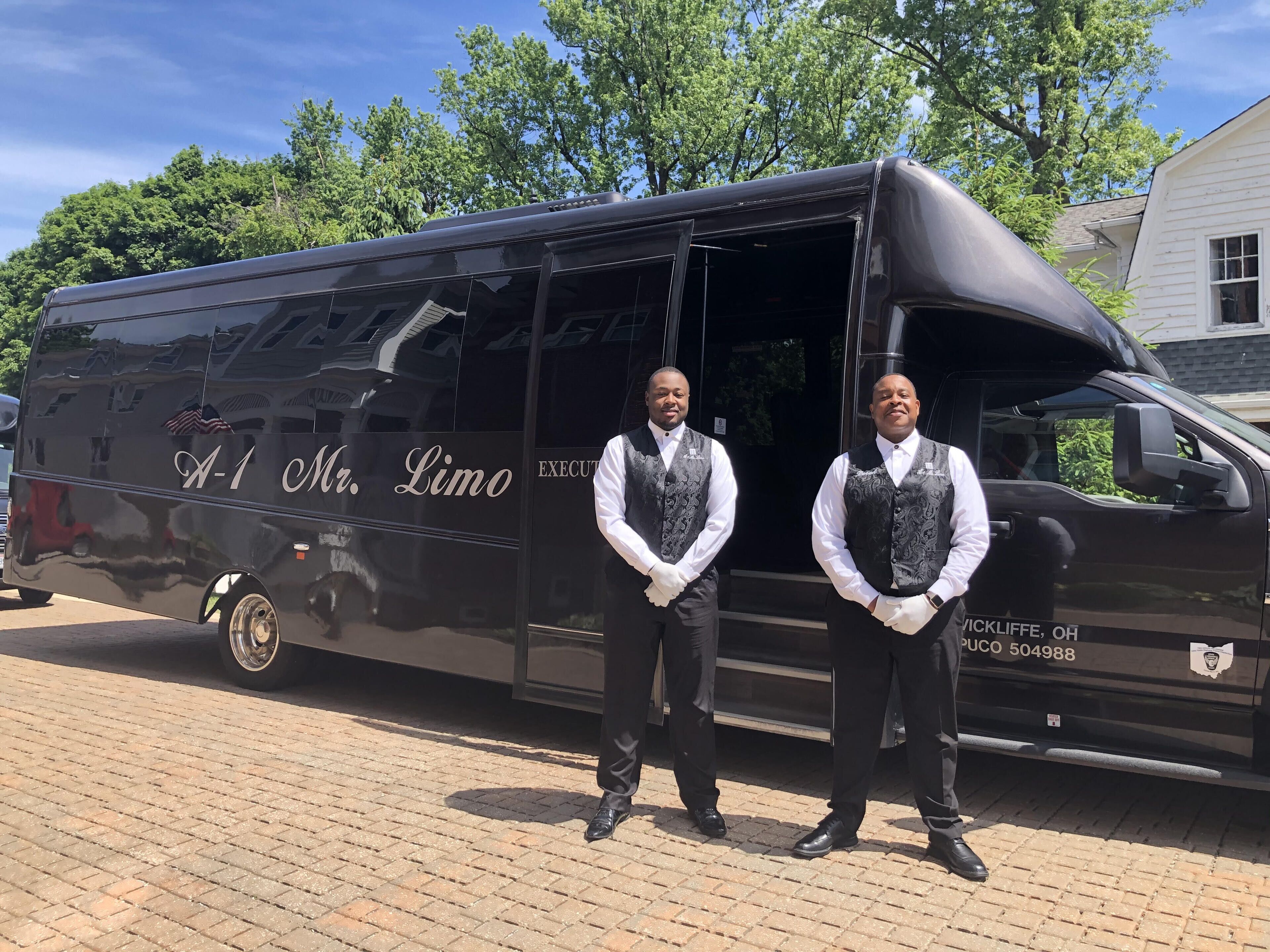 Dos hombres de pie frente a una camioneta negra con la leyenda "A-1 Mr. Limo".