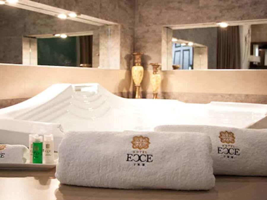 A hotel bathroom with a large bathtub, two towels with the hotel logo, and toiletries on a tray.