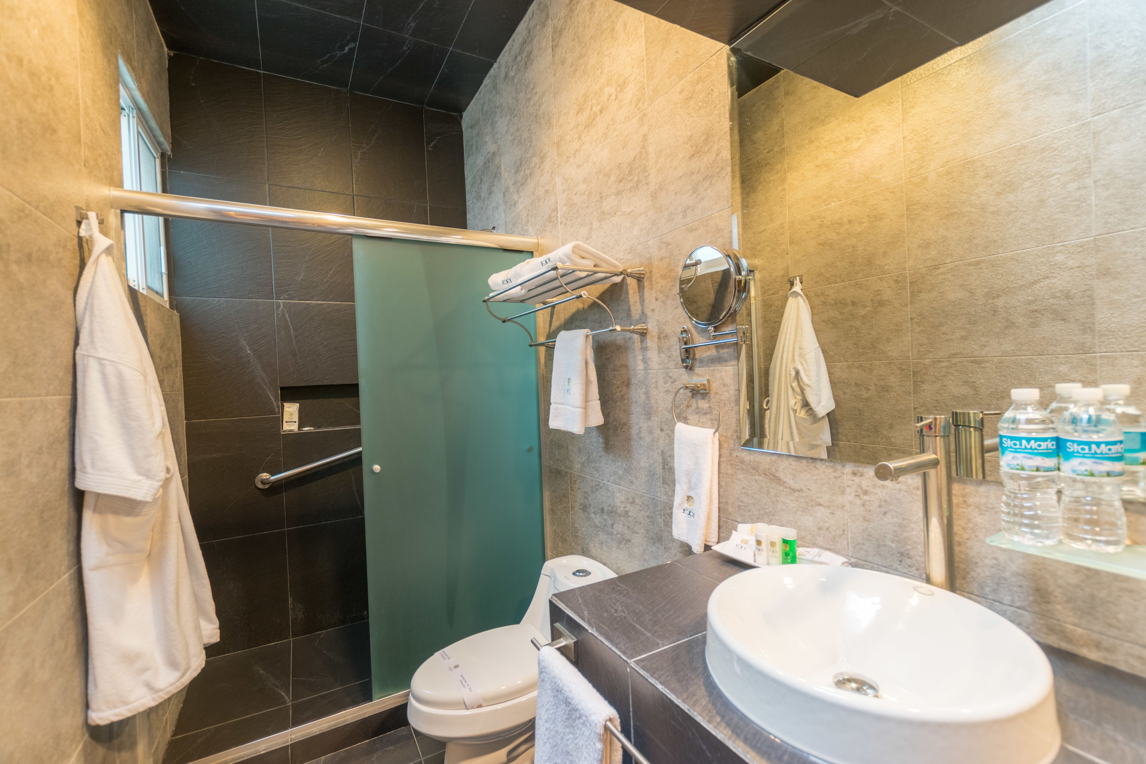 A modern bathroom with a glass shower enclosure, a white sink, and a mirror.