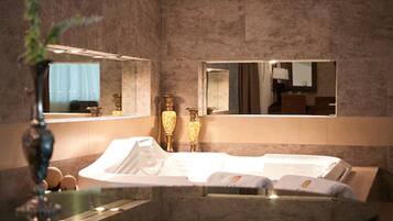 A modern bathroom with a bathtub, a large mirror, and a vase with flowers.