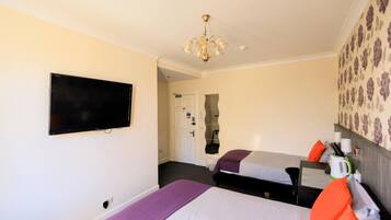 Una habitación de hotel con dos camas, televisión, candelabro y espejo.