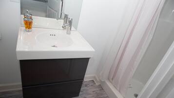 A bathroom with a white sink, dark cabinet, and a shower curtain.