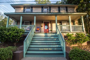A two-story building with a porch and a staircase leading to the entrance.