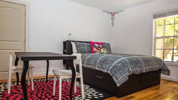 A bedroom with a bed, a desk, and a chair.