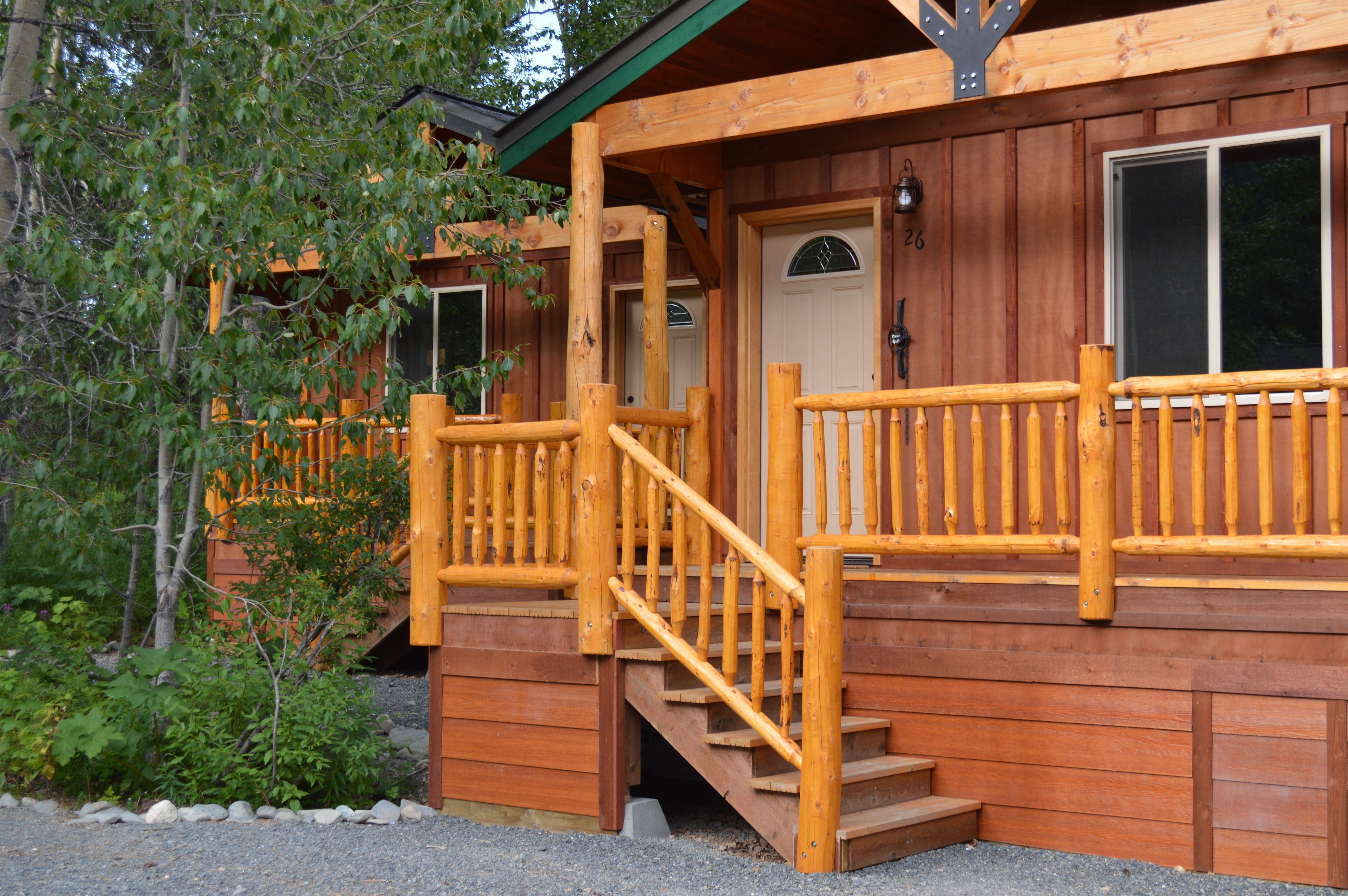 Une cabane en bois avec un escalier en bois menant à une véranda dotée d’une balustrade.