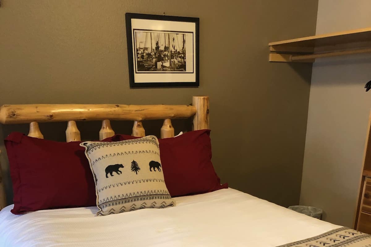 A bed with a wooden headboard, white bedding, and a patterned throw blanket.