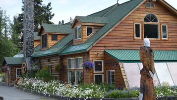Experience the charm of a traditional log cabin, complete with a stone chimney and garden surroundings.