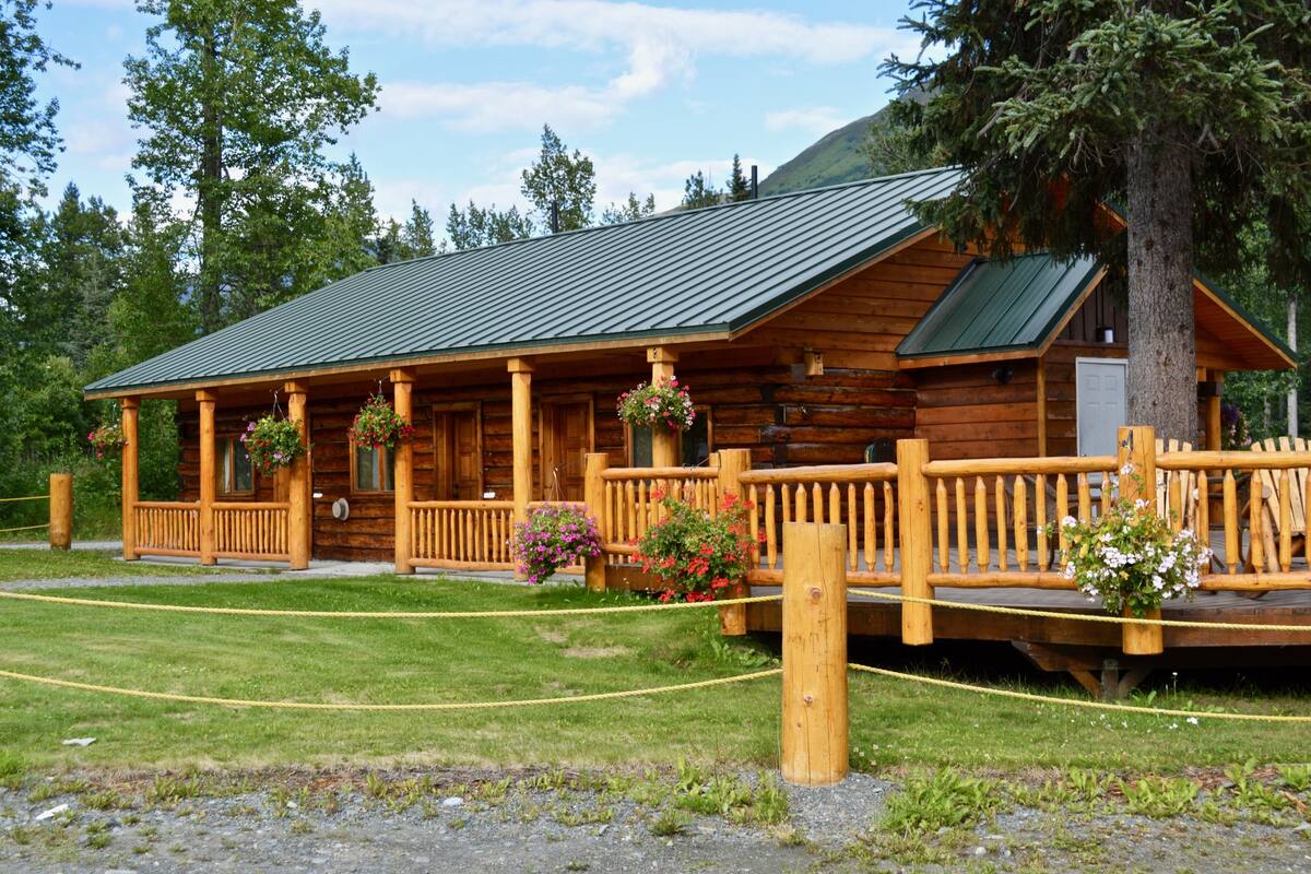 A log cabin with a porch, wooden railings, and flower baskets.