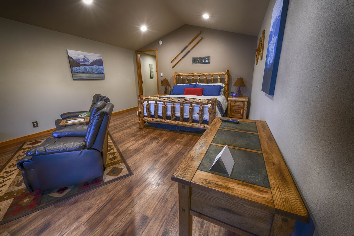 A bedroom with a wooden bed, a blue reclining chair, and a small table.