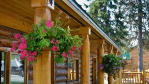 A wooden log cabin with hanging flower baskets and a wooden porch. - Summit Lake Lodge (Moose Pass)