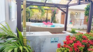 A pool area with a hot tub, a BBQ zone sign, and surrounding greenery. - Cabañas Green Yard (San Andrés)