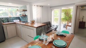 A modern kitchen with a dining area, a refrigerator, a sink, and a window overlooking a garden. - Cabañas Green Yard (San Andrés)