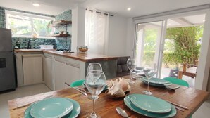 A kitchen with a refrigerator, sink, and wooden countertop. There is a dining table with plates and wine glasses. - Cabañas Green Yard (San Andrés)