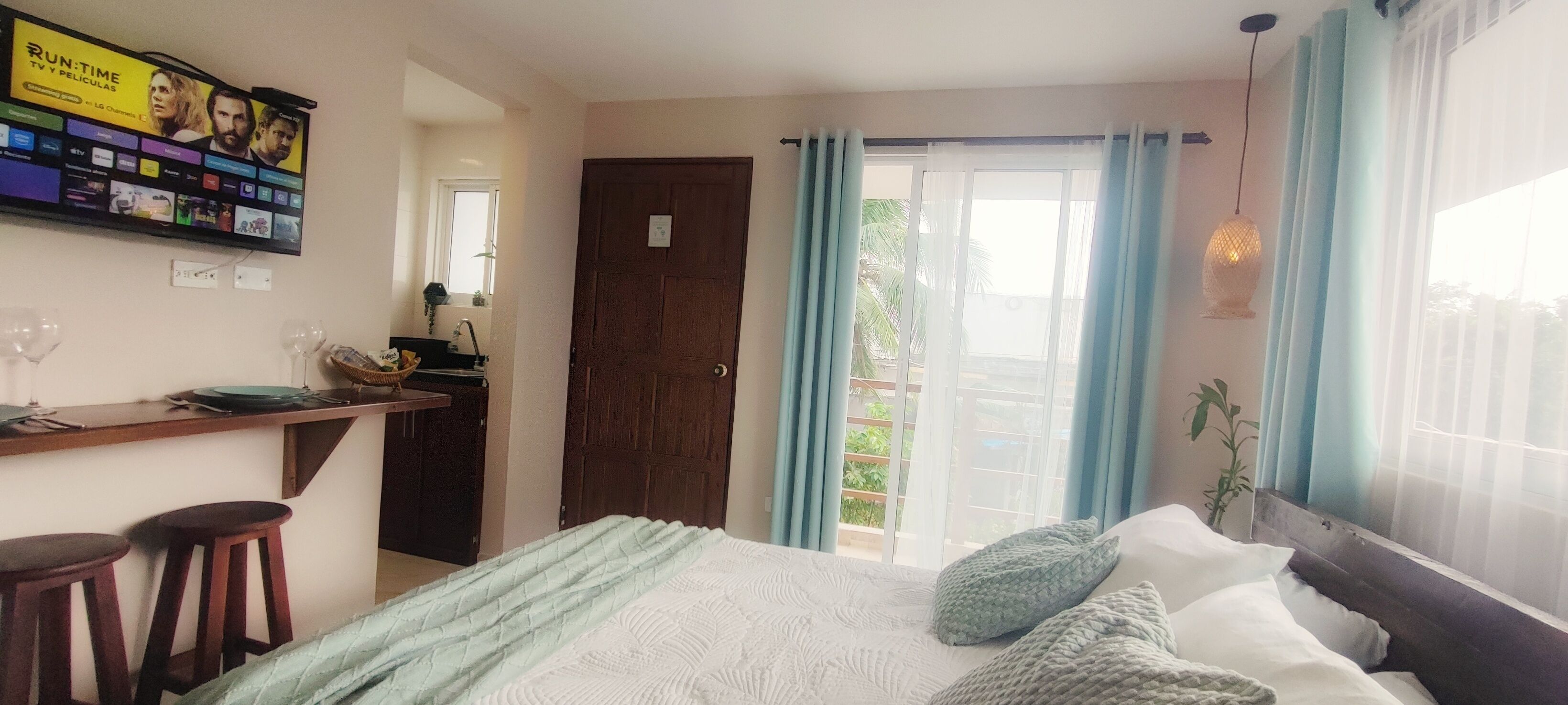 A bedroom with a bed, a desk, and a TV displaying a movie.