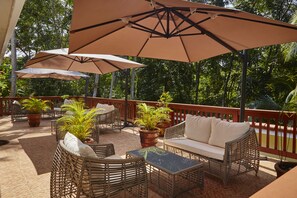 Une terrasse extérieure aménagée avec des meubles en osier, des plantes en pot et de grands parasols.