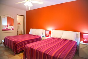 A hotel room with two beds, a ceiling fan, and a bathroom with a red towel rack.