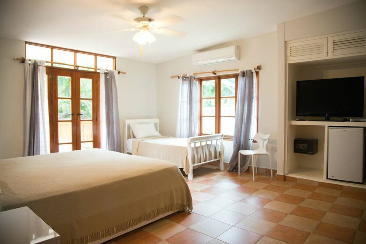 A bedroom with a bed, a desk, a chair, a television, and a refrigerator.