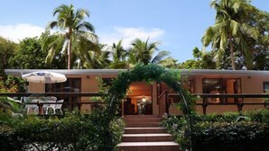A hotel entrance with a staircase, palm trees, and outdoor seating.