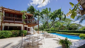 A two-story building with a balcony, a swimming pool, and outdoor seating.