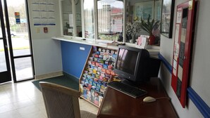 En receptionsdisk med en computer, en stol og en kalender på væggen.
