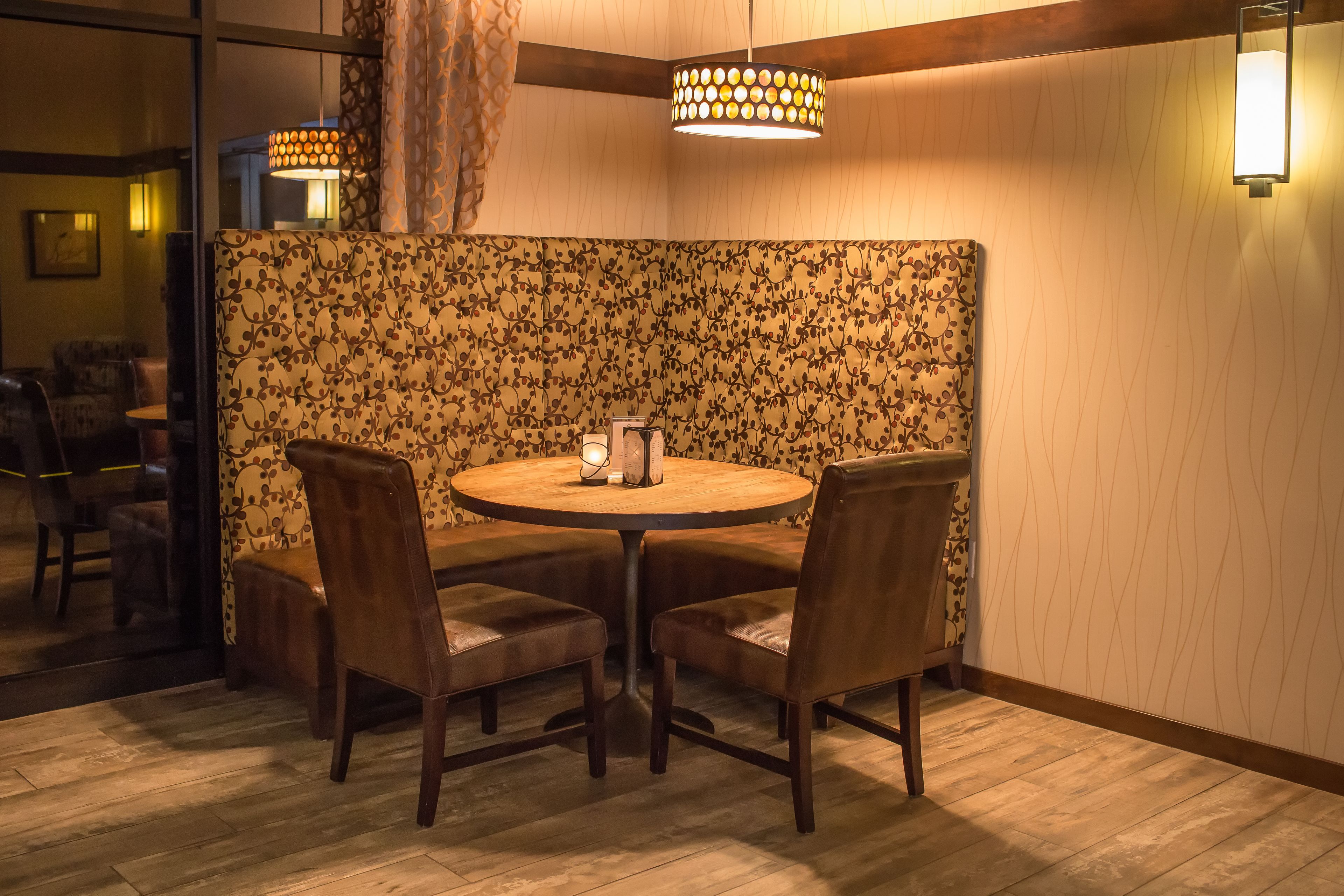 Un'accogliente sala da pranzo con un tavolo rotondo e quattro sedie, una parete divisoria decorata con motivi floreali e una moderna lampada a sospensione.