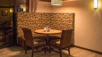 Un'accogliente sala da pranzo con un tavolo rotondo e quattro sedie, una parete divisoria decorata con motivi floreali e una moderna lampada a sospensione.