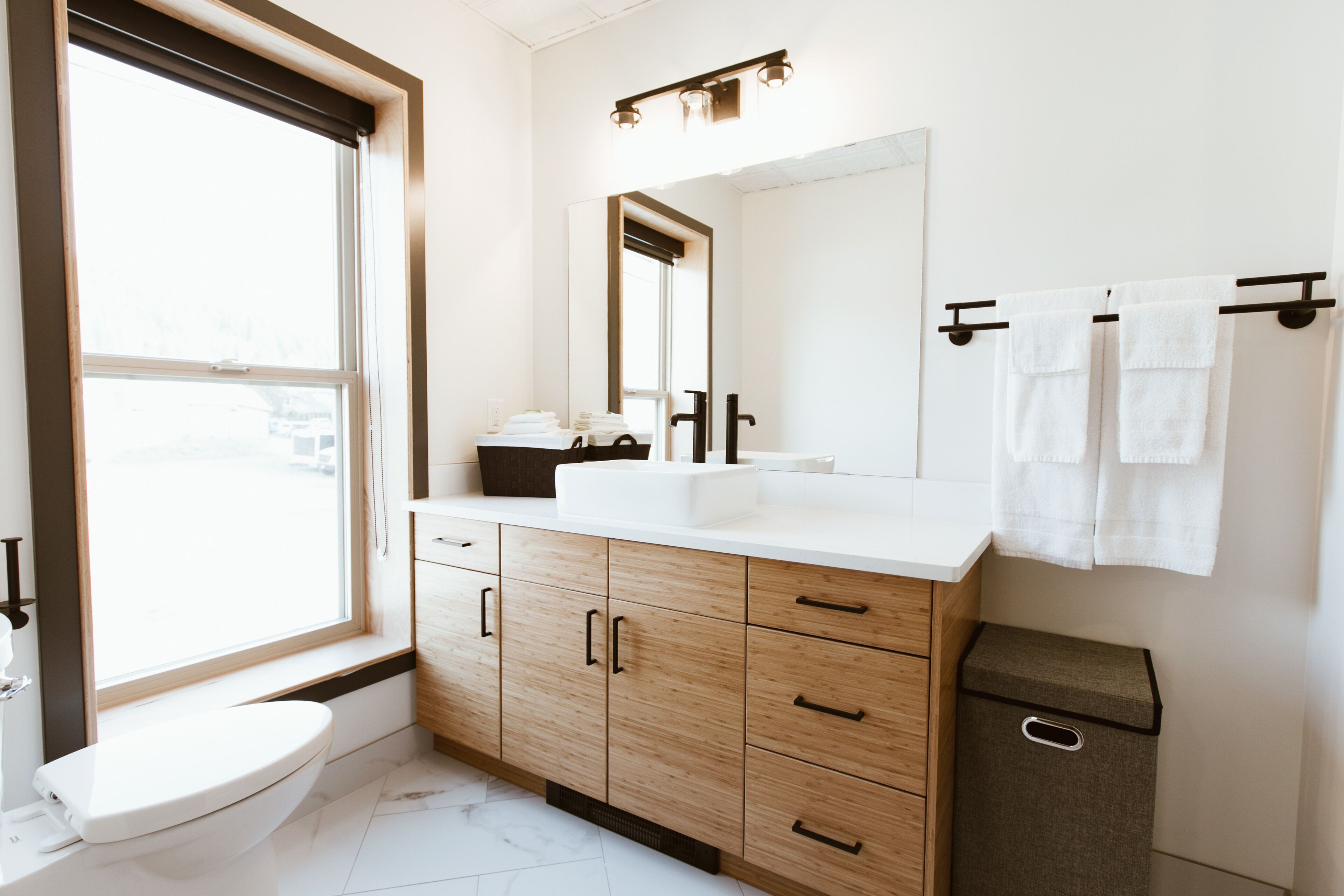Un baño moderno con inodoro, lavamanos, espejo y toallero.