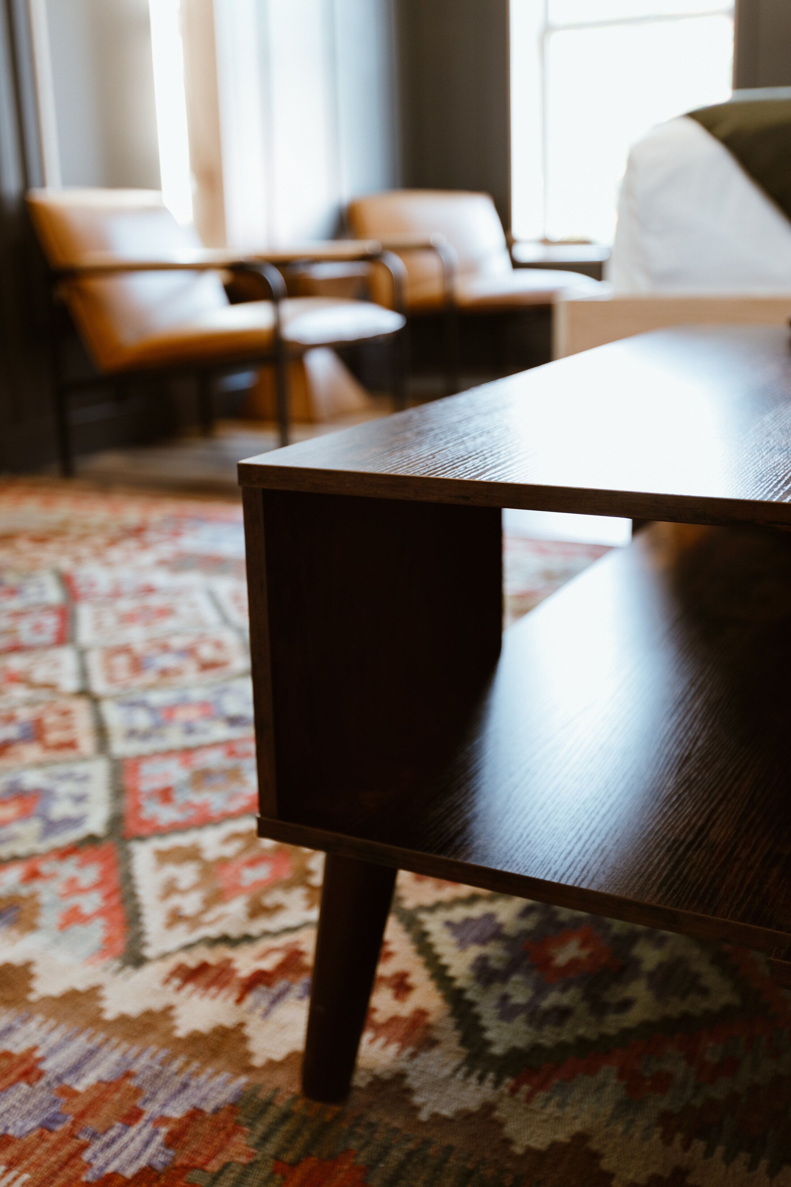 A wooden table with a dark finish in a room with patterned carpet and a sofa in the background.