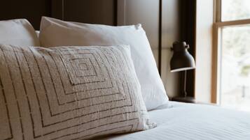 A neatly made bed with white linens and a patterned pillow.