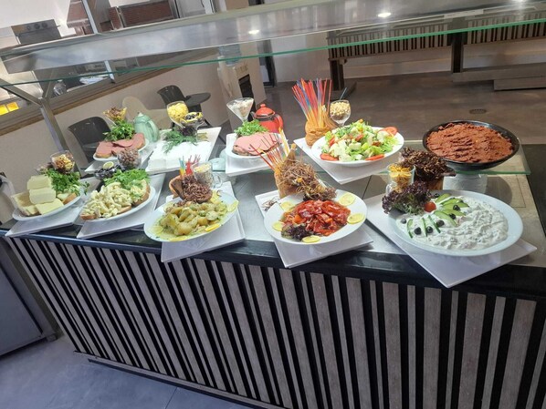 A buffet with various dishes, including salads, meats, and desserts.