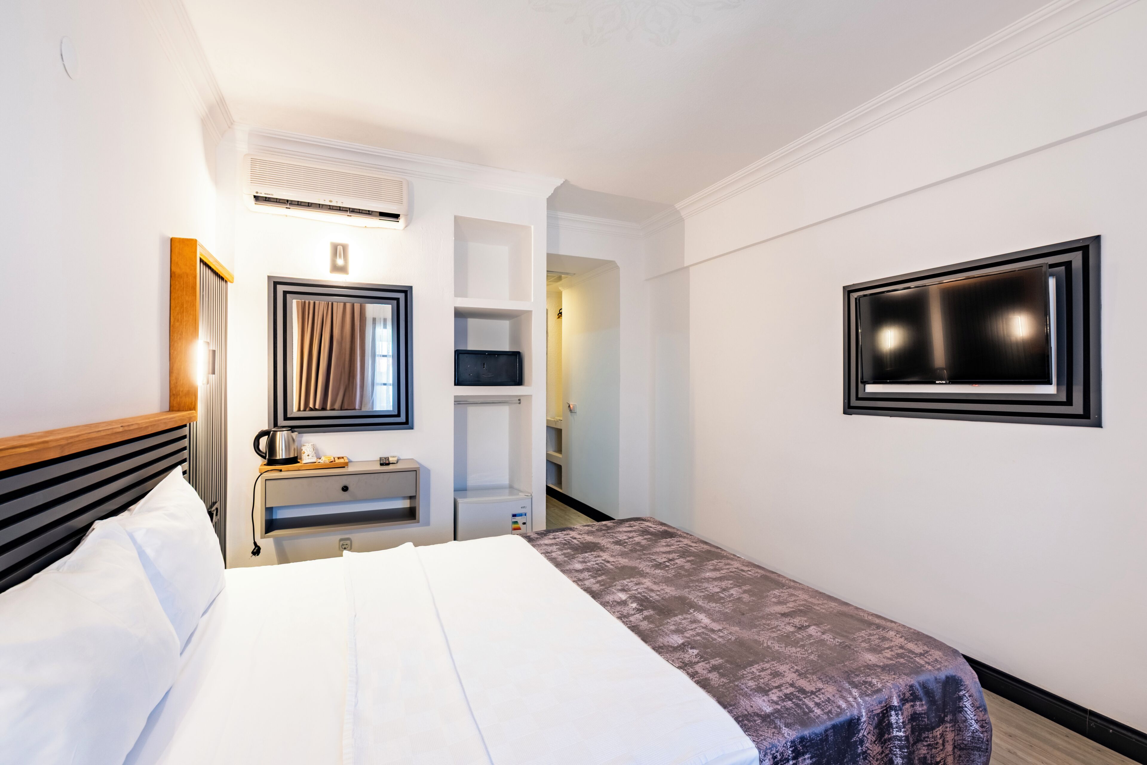 Habitació d'hotel amb llit, escriptori amb làmpada, televisió i armari.