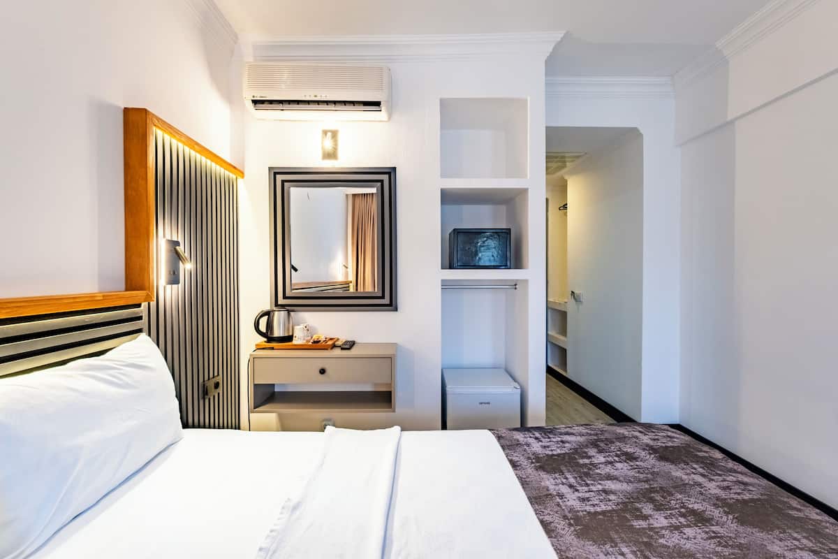 Une chambre d’hôtel comprenant un lit, une table de chevet, un miroir, une armoire et un petit meuble.