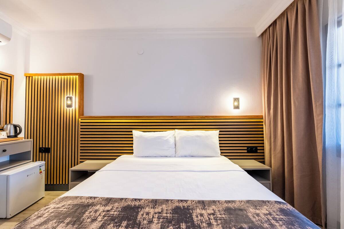 Une chambre d’hôtel comprenant un lit, une table de chevet, une lampe et une armoire.