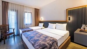 Ein Hotelzimmer mit zwei Betten, einem Sessel, einem Nachttisch und einer Wandleuchte.