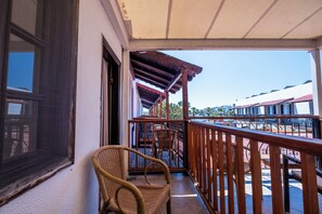A balcony with wicker chairs, a wooden railing, and a view of other buildings. - Costa Bitezhan Hotel (Bodrum)