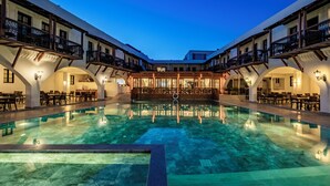 Ein Hotel mit einem zentralen Pool, mehreren Balkonen und überdachten Sitzbereichen.