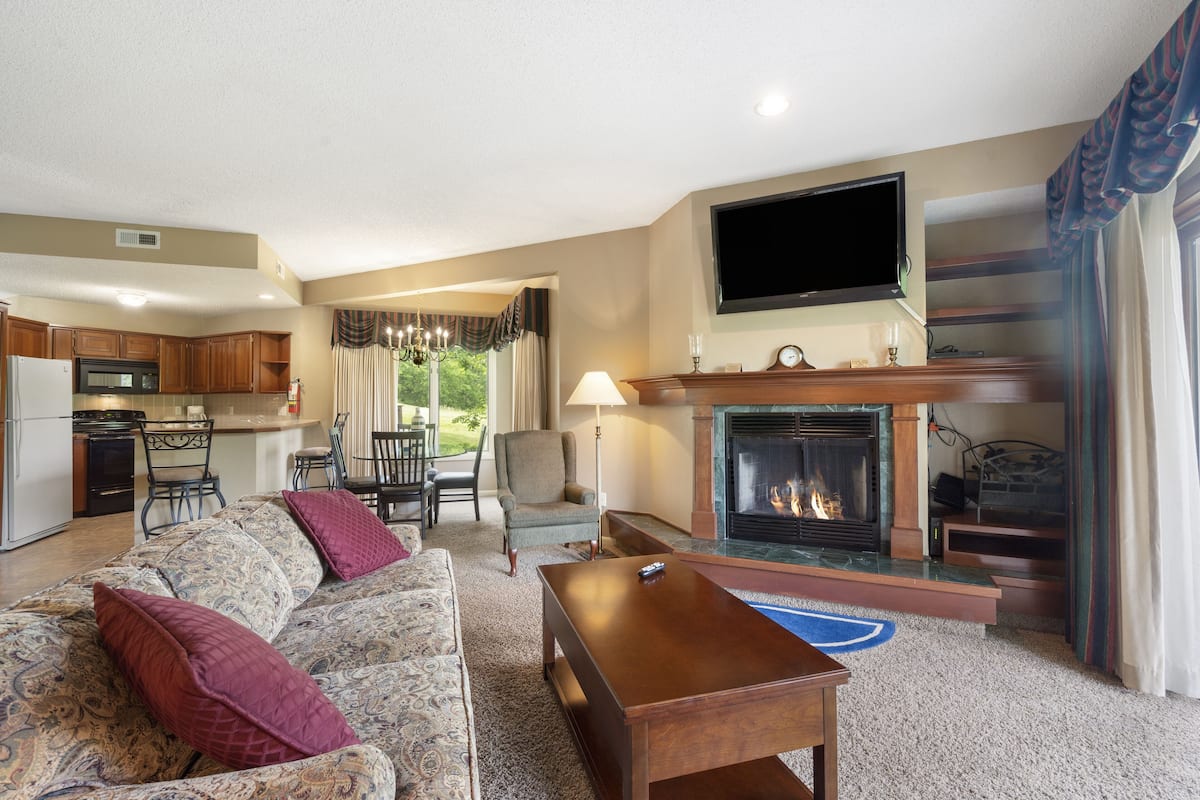 A living room with a fireplace, sofa, and a television.