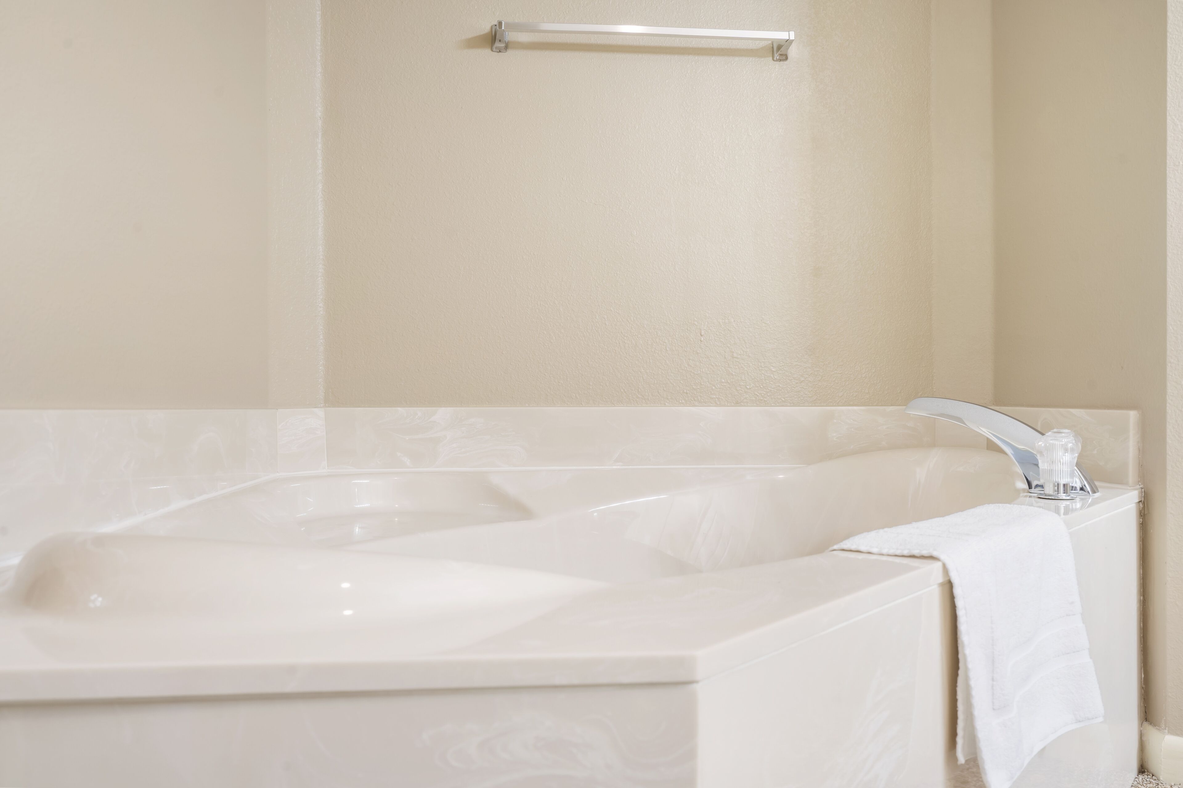 A bathroom with a large bathtub, a towel rack, and a modern faucet.