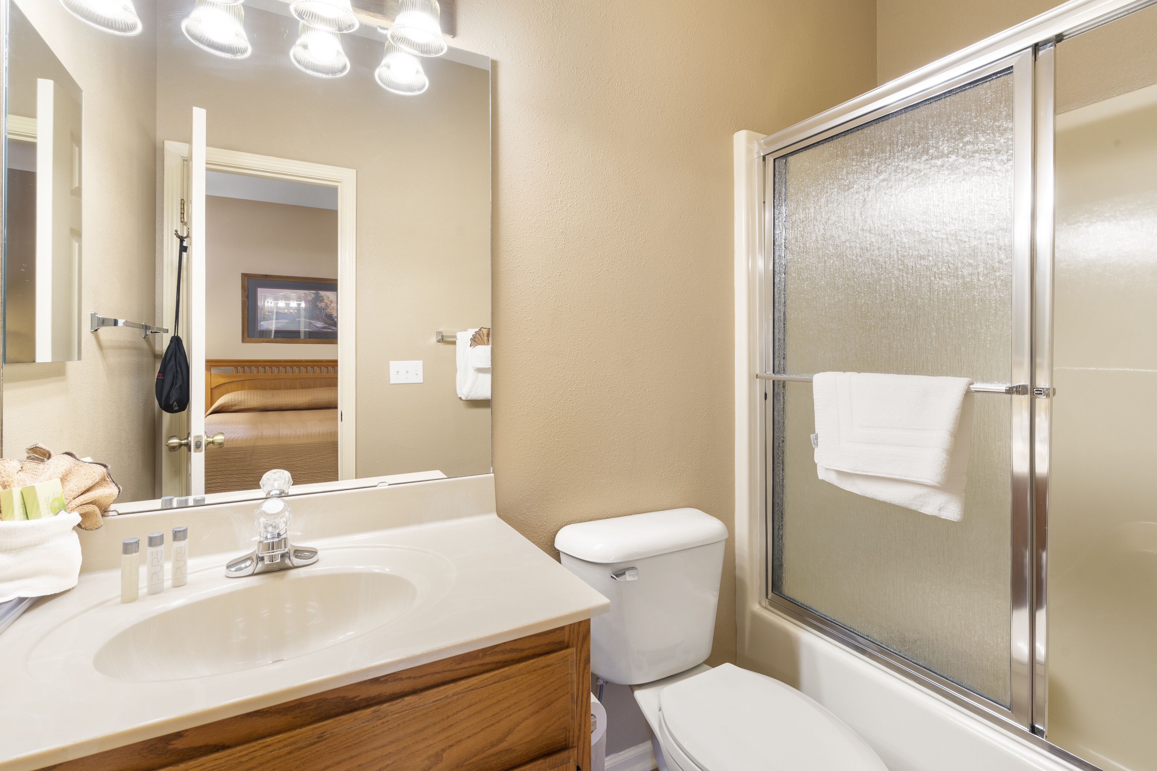 A bathroom with a sink, mirror, toilet, and shower.