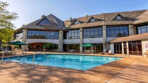 A large building with a swimming pool, outdoor seating, and a covered patio area. - Stonebridge Village Resort (Branson West)
