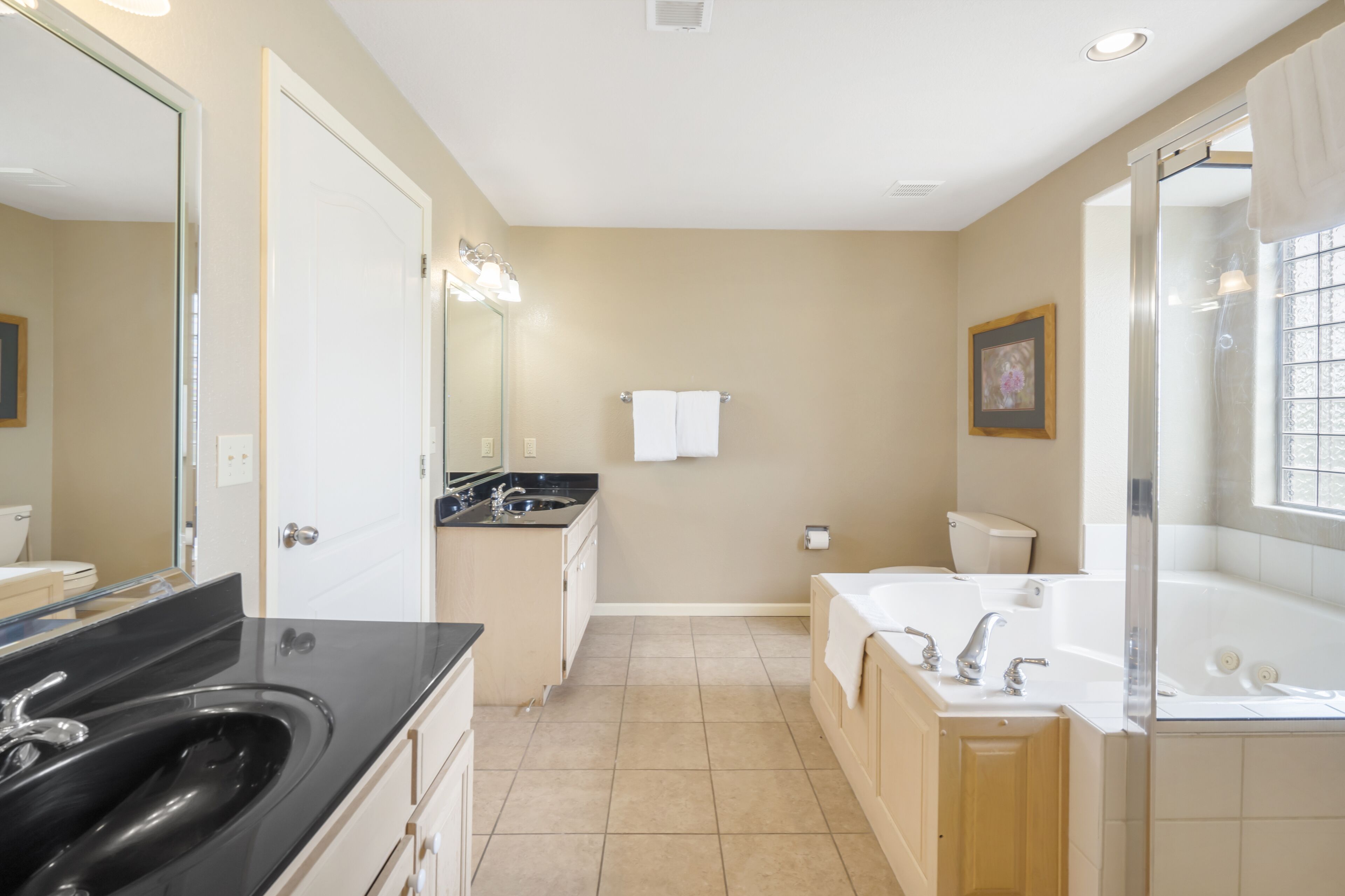 A modern bathroom with a double sink, a large mirror, a bathtub, and a shower.