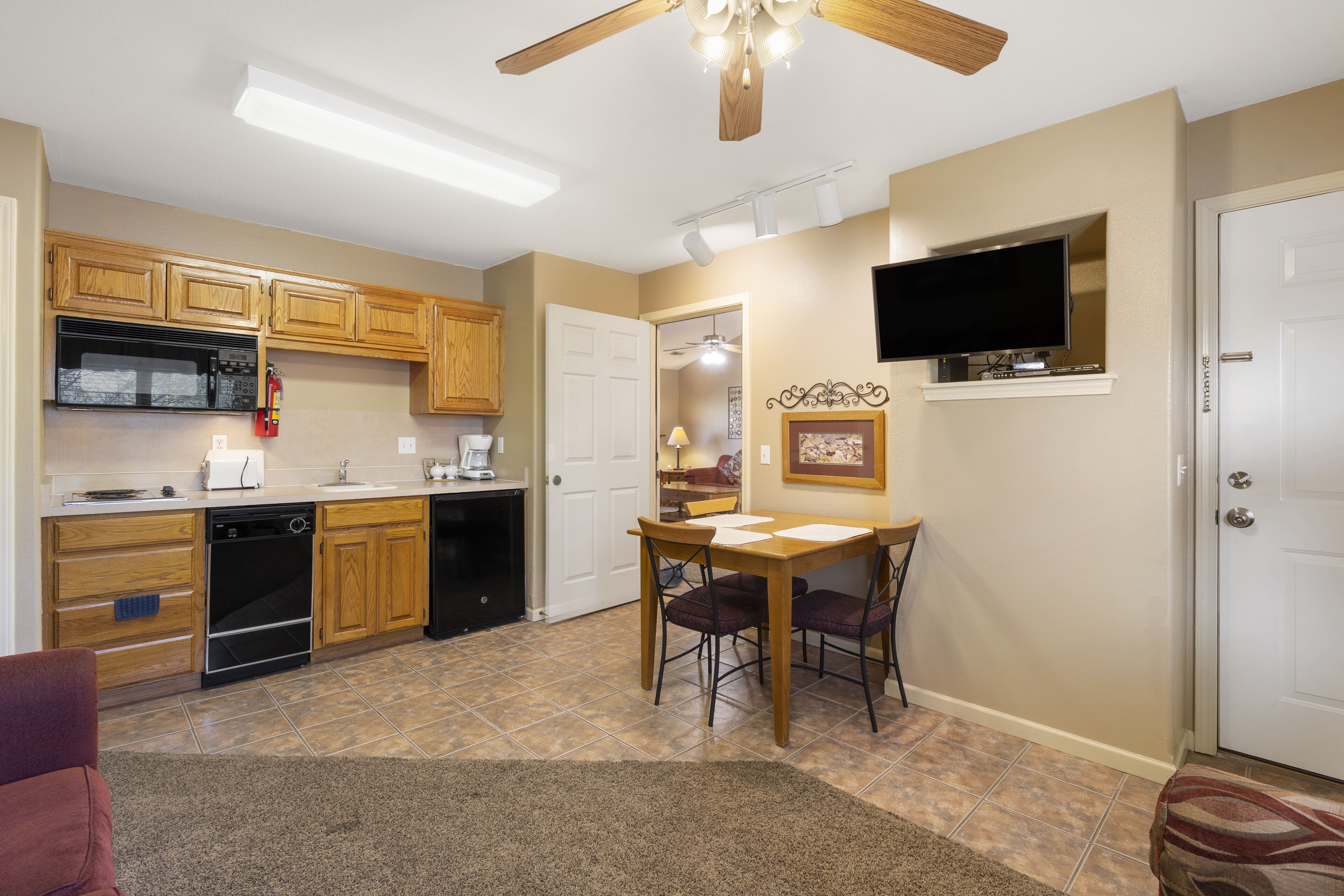 A kitchen with wooden cabinets, a microwave, a dishwasher, and a dining area with a table and chairs.