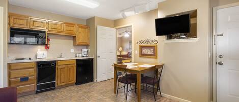 A kitchen with wooden cabinets, a microwave, a dishwasher, and a dining area with a table and chairs.